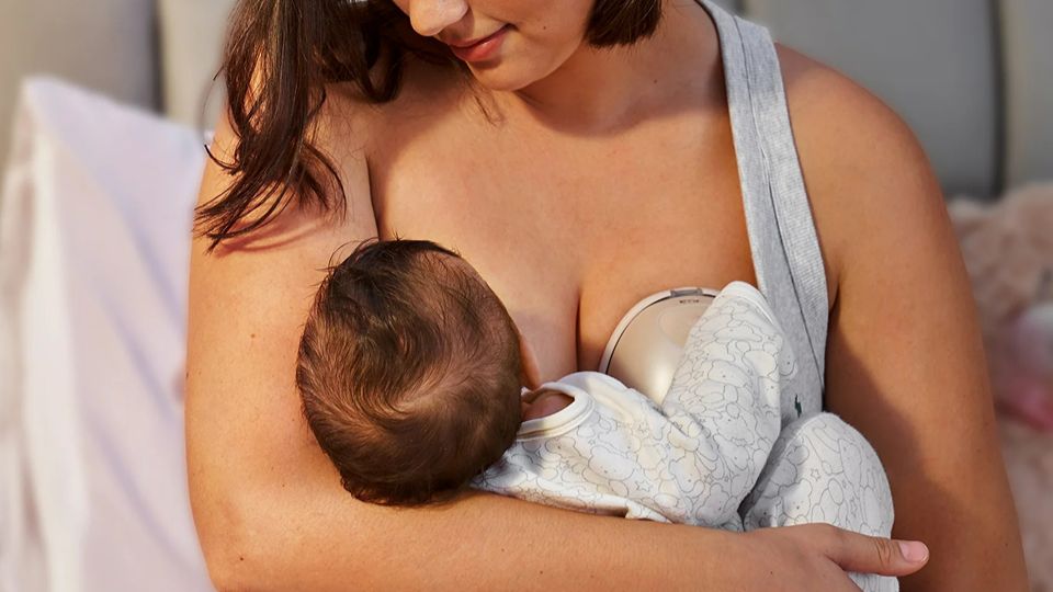 Mum nursing baby while pumping